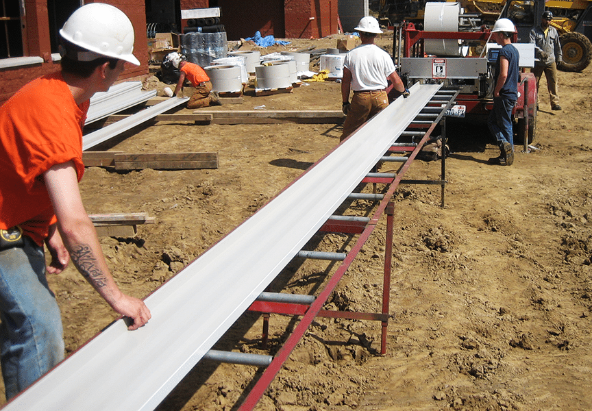 panel exiting portable roof panel machine at construction site