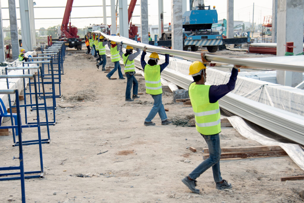 construction workers carrying metal roof panels 