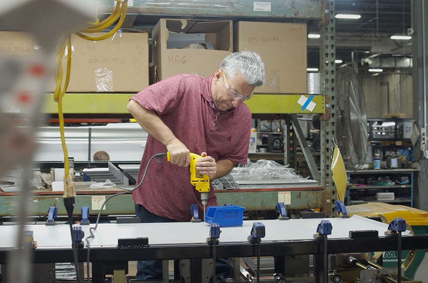 employee bolting down cover for a seamless gutter machine