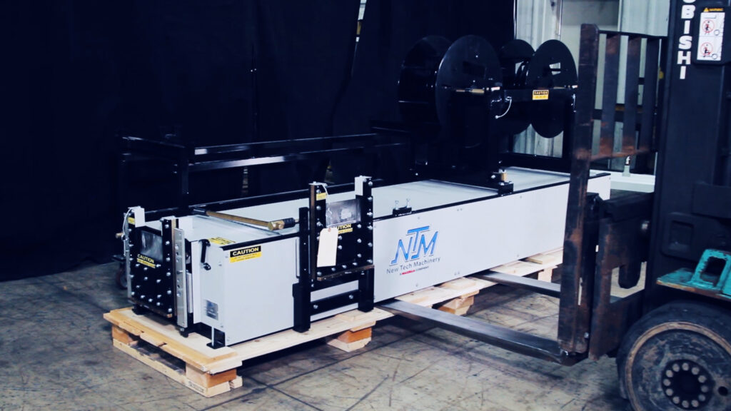Forklift preparing to pick up a gutter machine on a wooden pallet