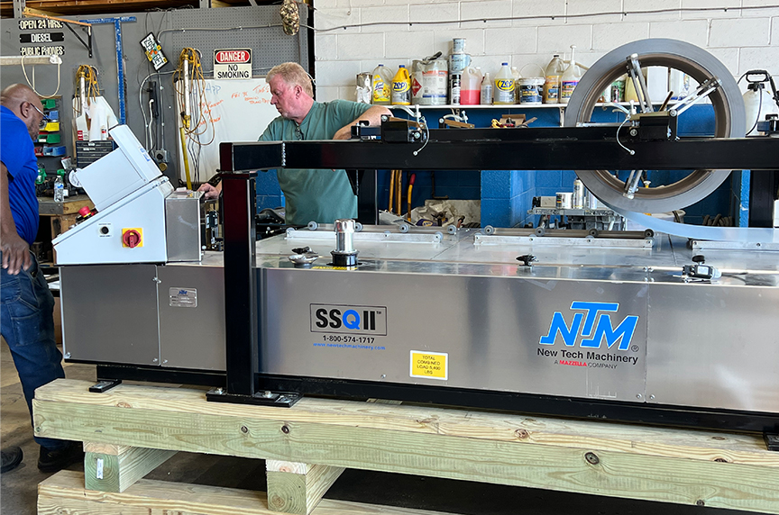 service technician operating SSQ II roof panel machine on pallets inside shop