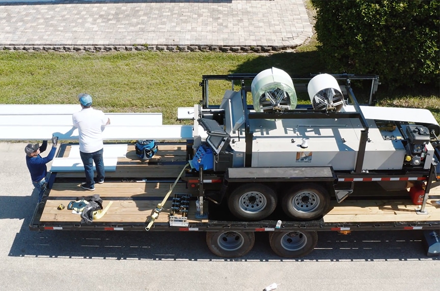 portable roof panel machine on trailer at job site with material going through