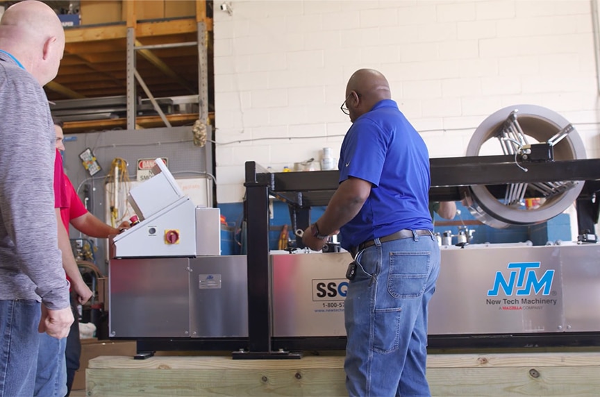 service technician walking around SSQ II MultiPro roof panel machine with coil loaded