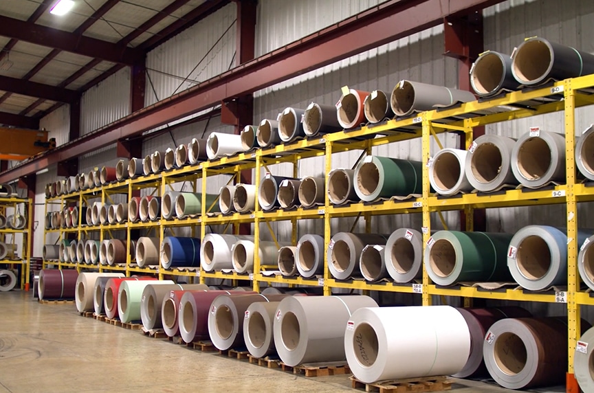 stacks of rolled metal coil on racks in plant