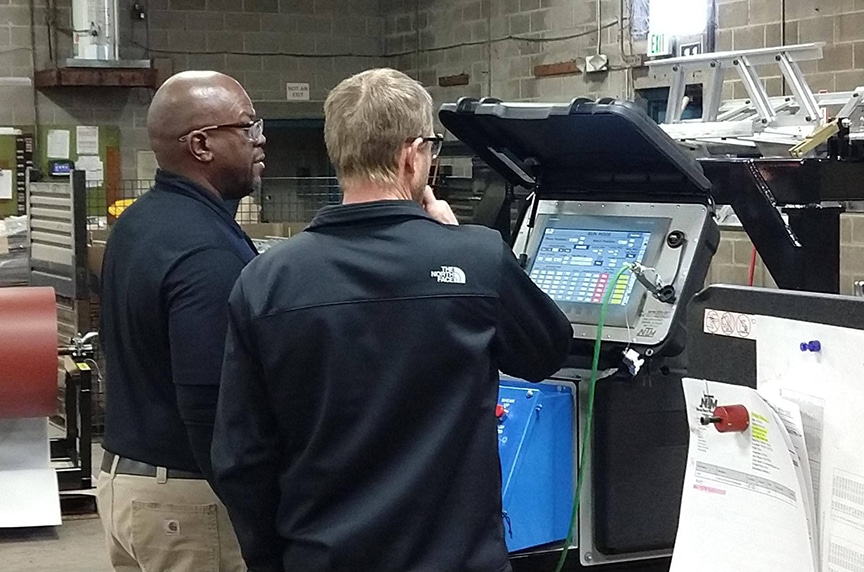 Service technician looking at computer controller on a portable rollforming machine