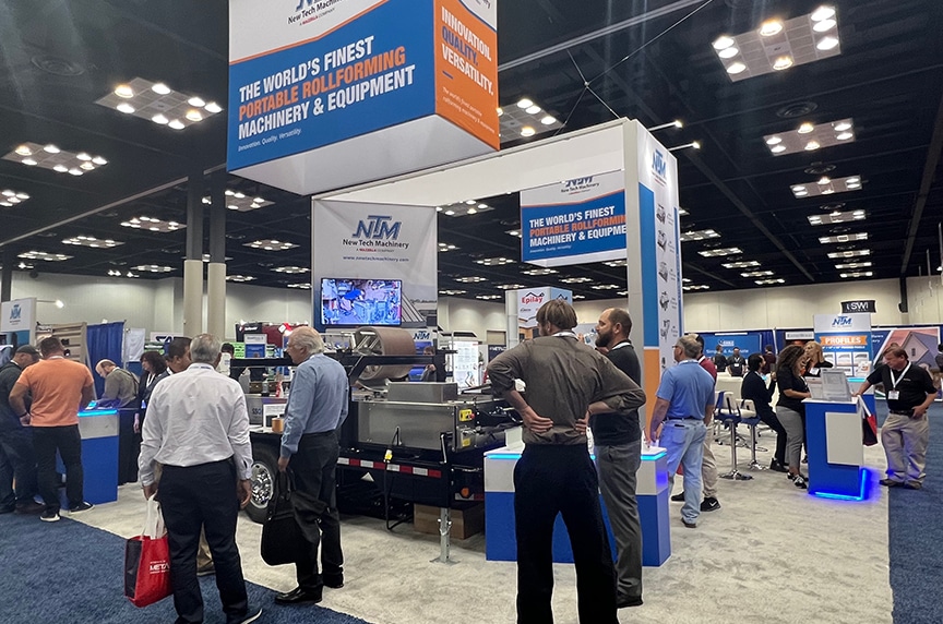 people standing around a carpeted new tech machinery booth at a convention