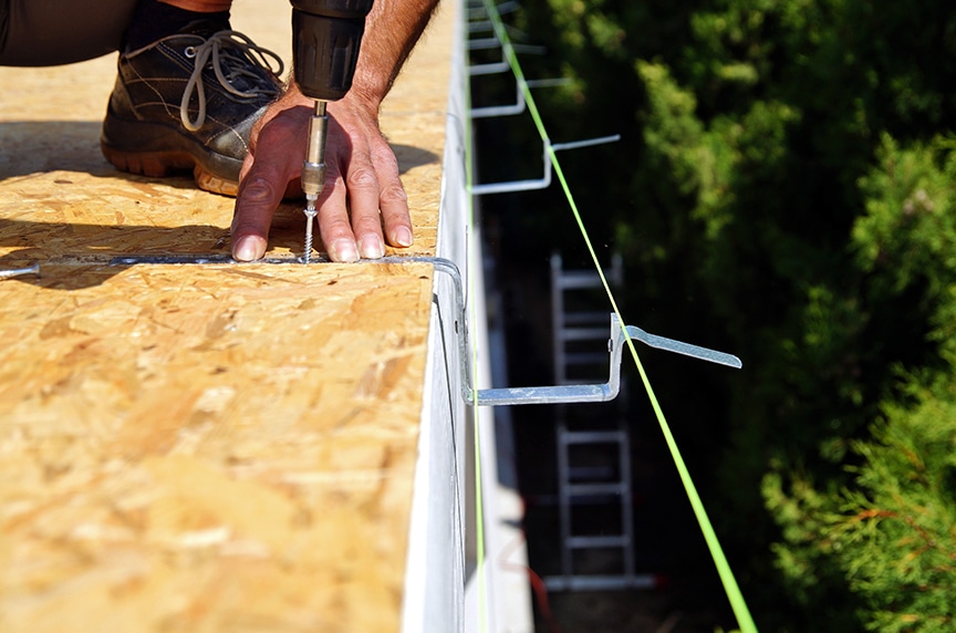 brackets hanging from a building roof for a gutter installation