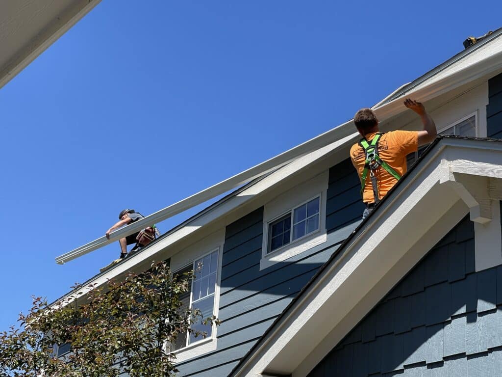 Workers installing gutters on a home.