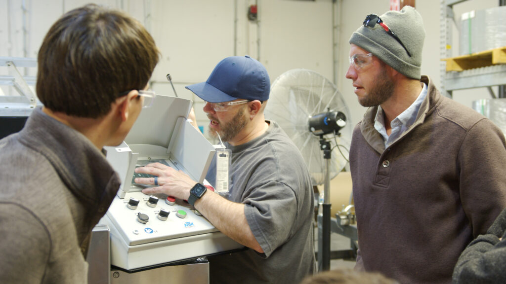 NTM technician training two operators on UNIQ controller.