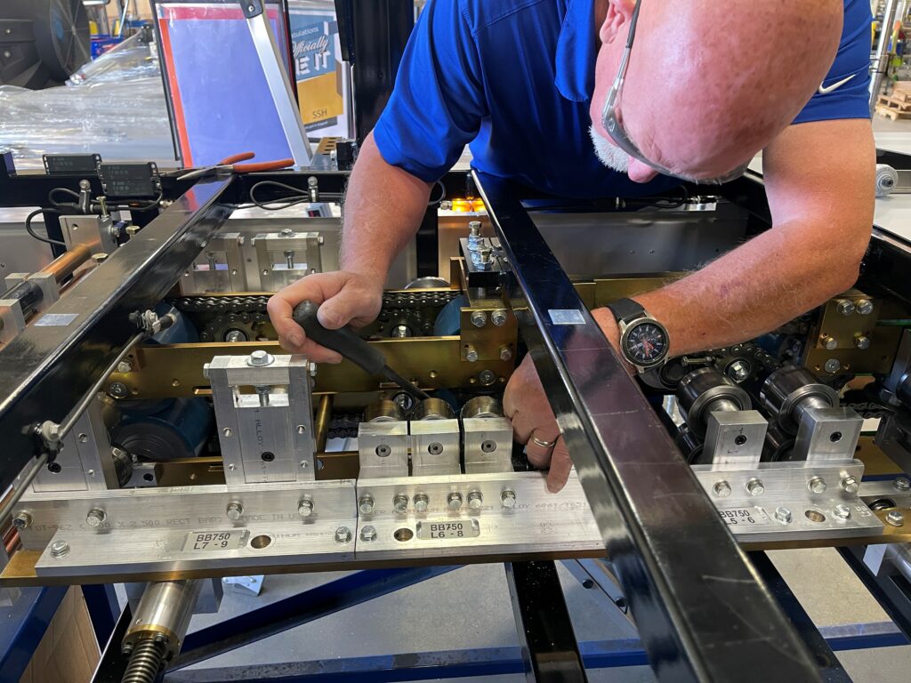 Machinist making an adjustment to a roller in an SSQ II Roof Panel machine.