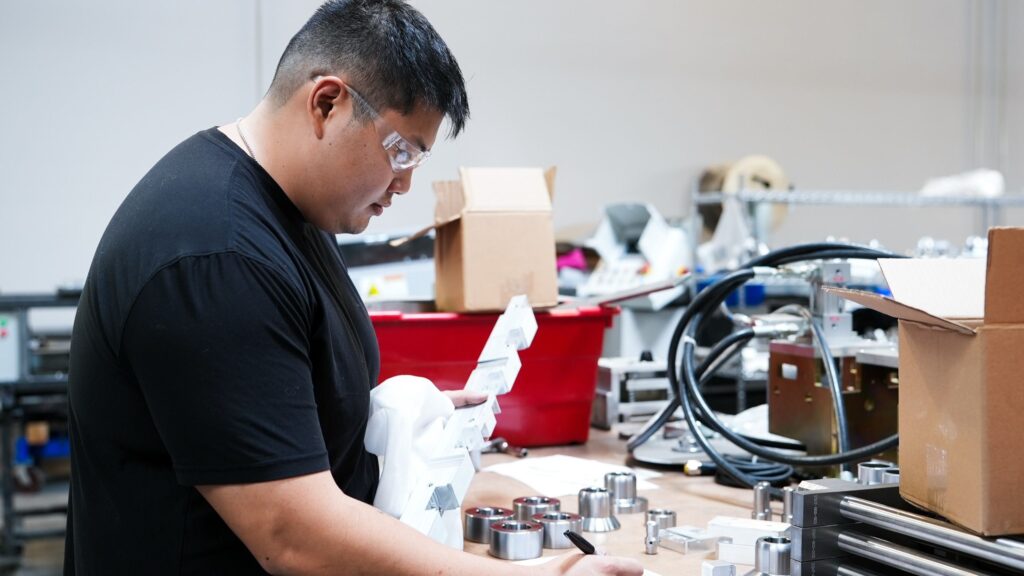 NTM engineer at a workstation, reviewing CAD drawings of a rollformer mechanism.