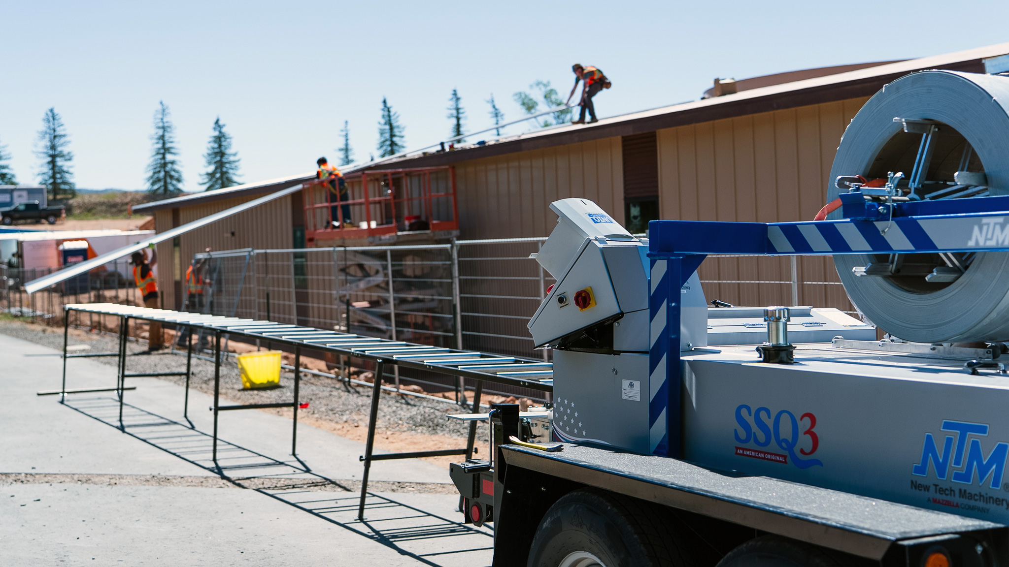 NTM operator feeding a metal panel into an SSQ3 portable rollformer on a jobsite